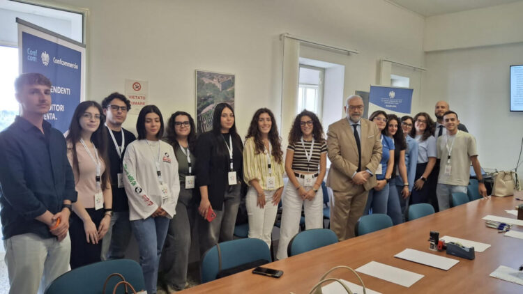 Giovani volontari del Servizio civile in posa nella sala riunioni di Confcommercio Ragusa, accanto a un tavolo e a roll-up blu