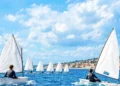 Settimana della vela: giovani su derive Optimist in regata sotto costa. Immagine generata con intelligenza artificiale