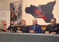 Funzionari in divisa e un uomo in giacca blu al tavolo della conferenza stampa nella Questura di Caltanissetta