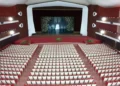 Platea del Teatro Duemila di Ragusa con poltrone rosse e bianche, balconate laterali e palco con sipario rosso aperto