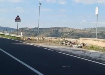 Telecamera su palo in una piazzola della Ss 194 a Ragusa, con rifiuti abbandonati vicino al muretto e colline sullo sfondo