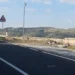 Telecamera su palo in una piazzola della Ss 194 a Ragusa, con rifiuti abbandonati vicino al muretto e colline sullo sfondo