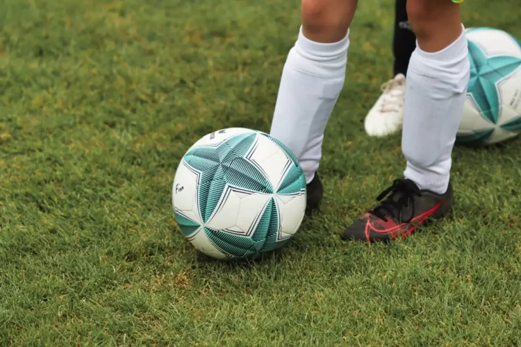 Pallone bianco e verde sul prato accanto ai piedi di un giocatore, foto illustrativa del Trofeo Nuccio Cappadona