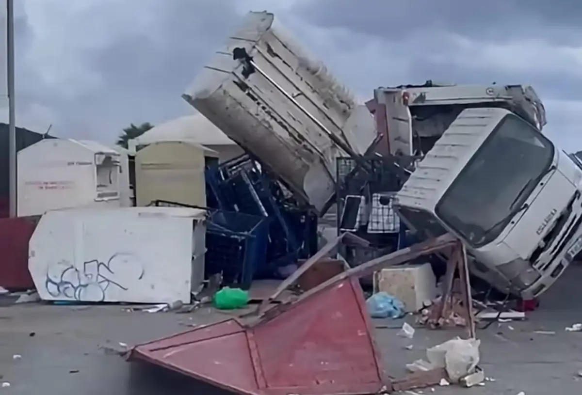 Camion ribaltato e cassonetti rovesciati su un piazzale dopo la tromba marina a Marsala, tra rifiuti e lamiere sparsi a terra