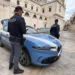 Due agenti della Polizia di Stato accanto a un'auto di servizio in una piazza lastricata davanti a una chiesa barocca