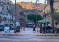 Turismo d’estate a Modica: passanti e tavolini all’aperto in centro, sullo sfondo le case di Modica Alta al tramonto