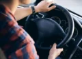 Ragazzo con camicia a quadri alla guida di un'auto, mani sul volante, come il ventenne denunciato a Vittoria