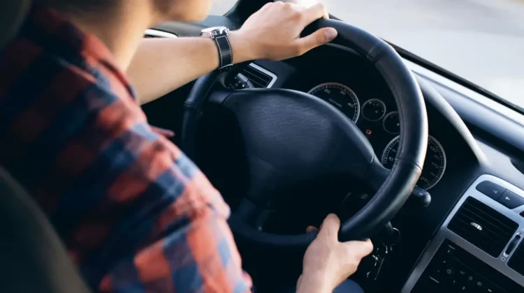 Ragazzo con camicia a quadri alla guida di un'auto, mani sul volante, come il ventenne denunciato a Vittoria