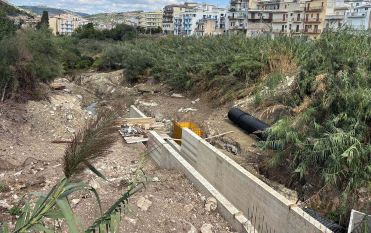 Muri in cemento del nuovo canale e un tubo nero corrugato tra i canneti, nel cantiere di valle di via Noce a Scicli