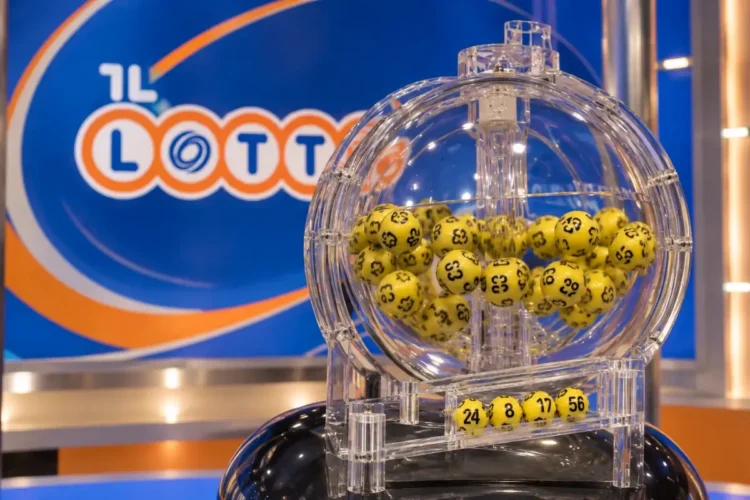Urna trasparente del lotto con palline gialle numerate e quattro numeri estratti, 24, 8, 17 e 56, davanti al logo Lotto
