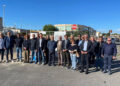 Cantiere nella zona artigianale di Ragusa: mini escavatore, recinzioni arancioni e segnale di divieto su una strada asfaltata