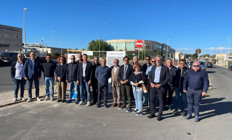 Cantiere nella zona artigianale di Ragusa: mini escavatore, recinzioni arancioni e segnale di divieto su una strada asfaltata
